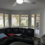 White plantation shutters installed on bedroom windows in a Central Coast home, providing privacy, airflow, and classic styling