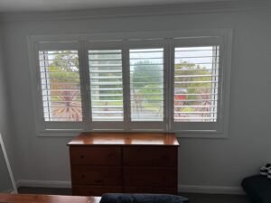 Four panel plantation shutters in lounge room, custom window coverings for privacy and light control.