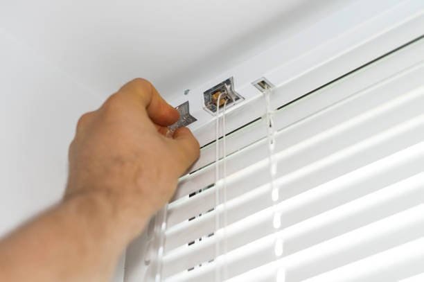 Man installing white Venetian blinds on a window – Central Coast home installation