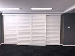 Four panel sliding door plantation shutters on display in showroom.