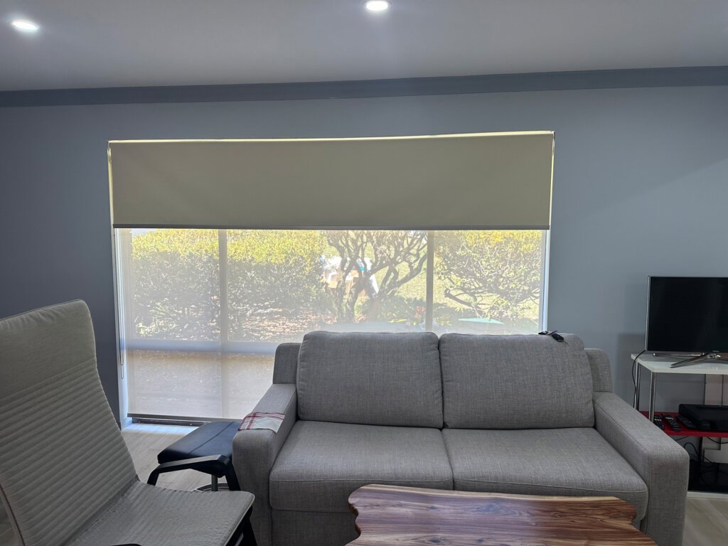 Custom roller blinds installed in a bright coastal living room with natural light and ocean views on the Central Coast.