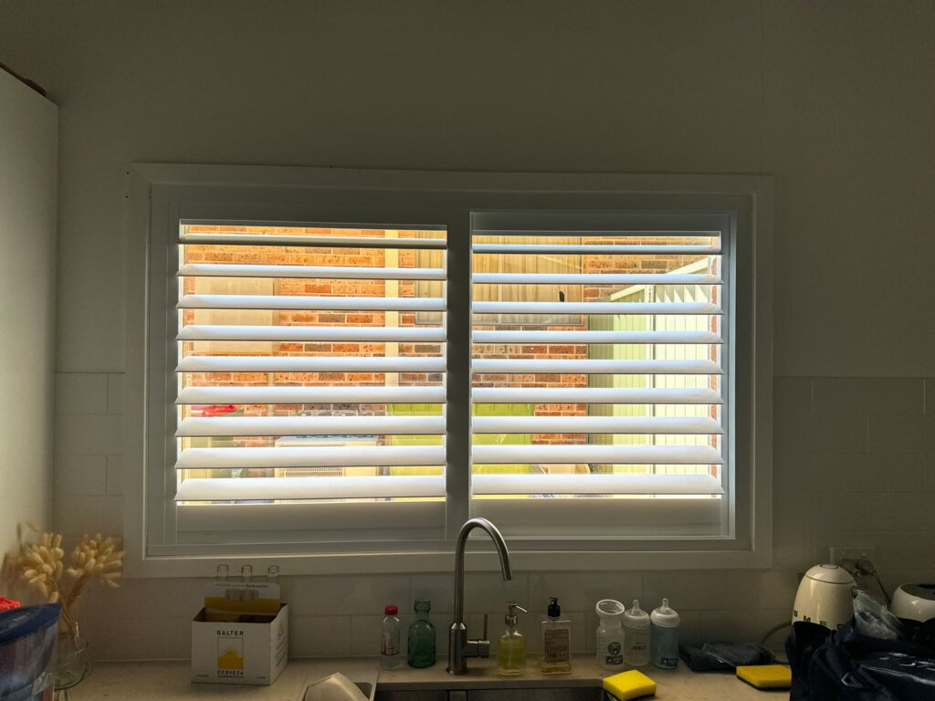 Modern white PVC plantation shutters installed in a bright living room — showing why are PVC plantation shutters good for light control and moisture resistance.