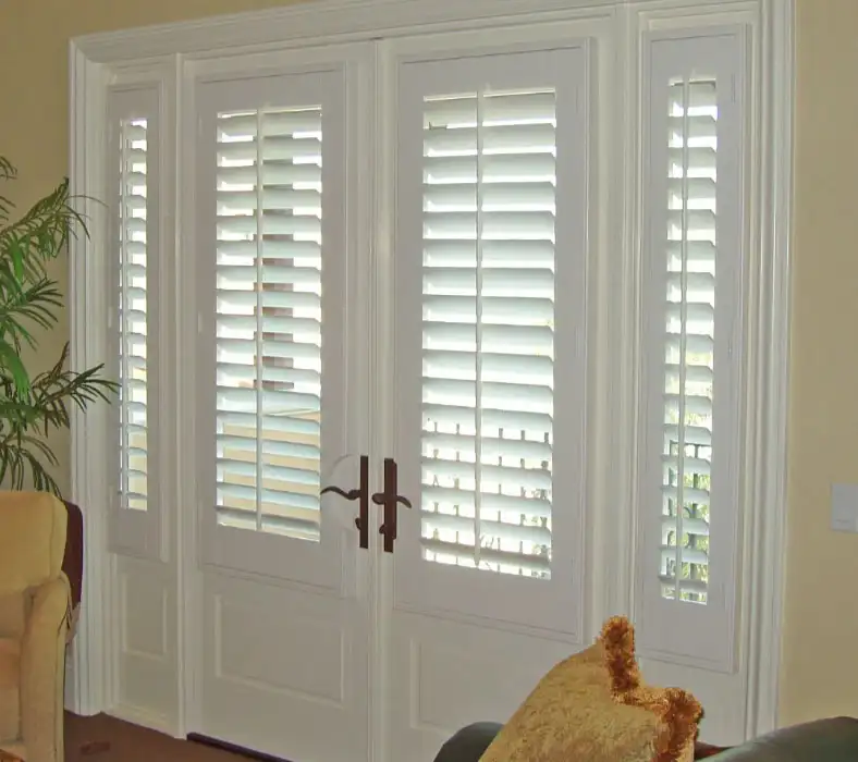 Plantation shutters for French doors with custom handle cut-outs, offering privacy and light control.