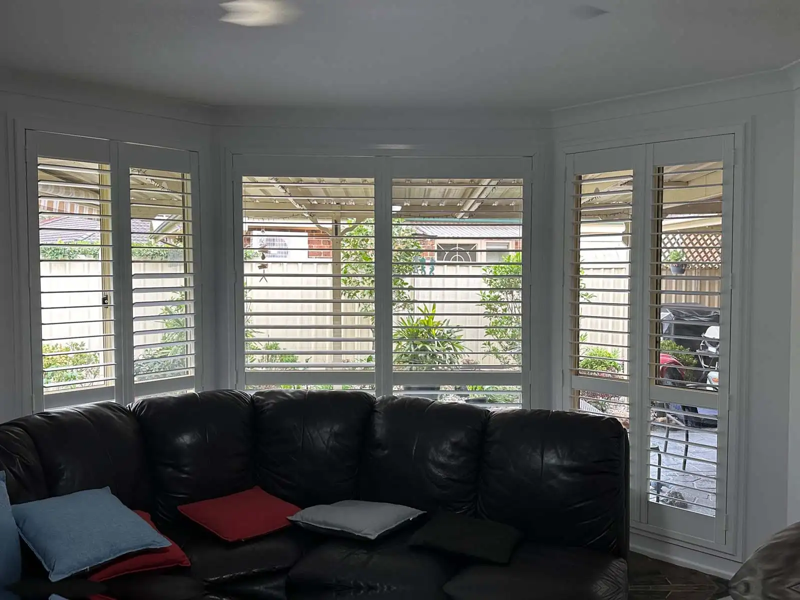 White plantation shutters installed on bay windows in a Central Coast living room