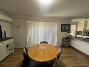 Modern dining room with custom vertical blinds filtering soft daylight – Central Coast installation by The Blind Crew.