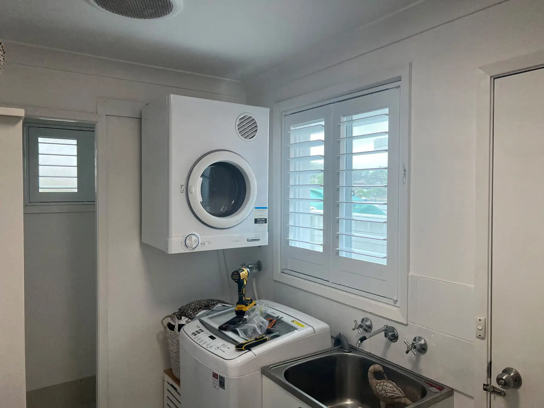 Plantation shutters used as Laundry Blinds in a wide laundry view, providing light control and privacy