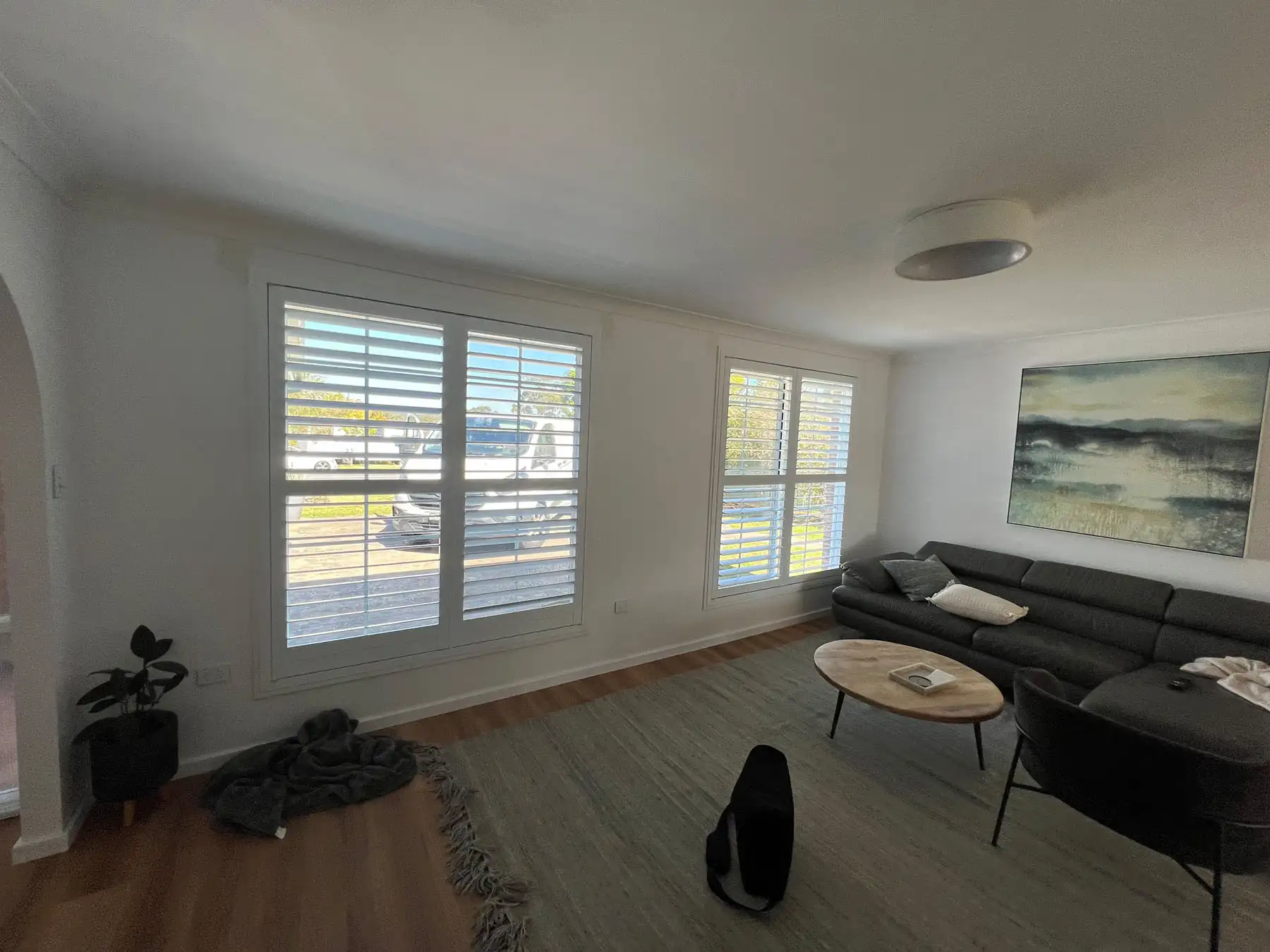 Plantation shutters used as living room blinds in a wide living room view, providing light control and privacy