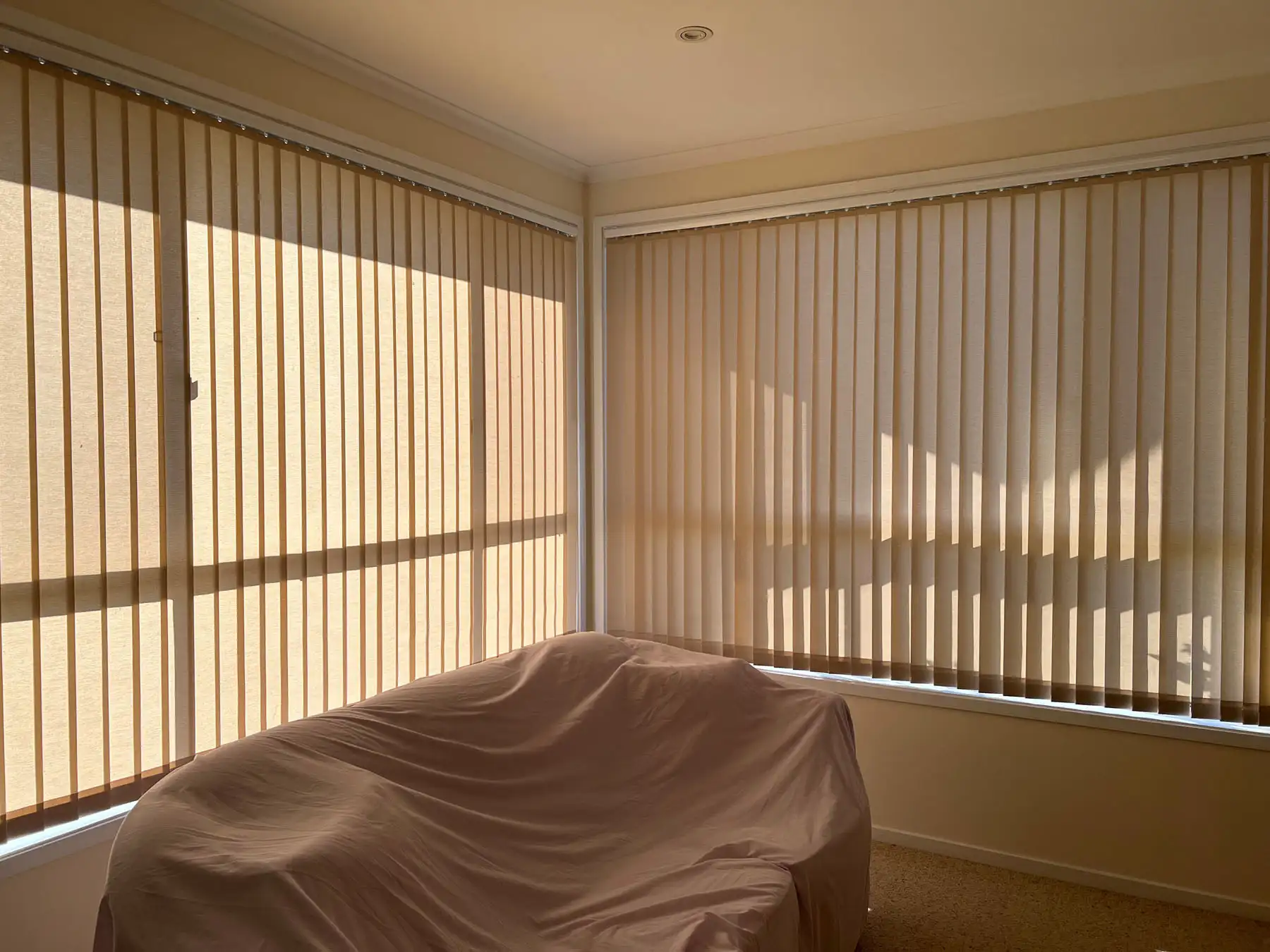 Vertical blinds installed as blinds for corner windows in a wide interior view, providing adjustable light control